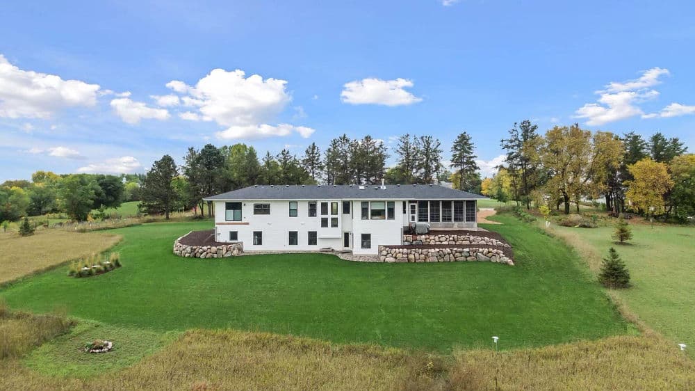 Spacious modern home on green land with trees under a blue sky. Ideal for peaceful living.