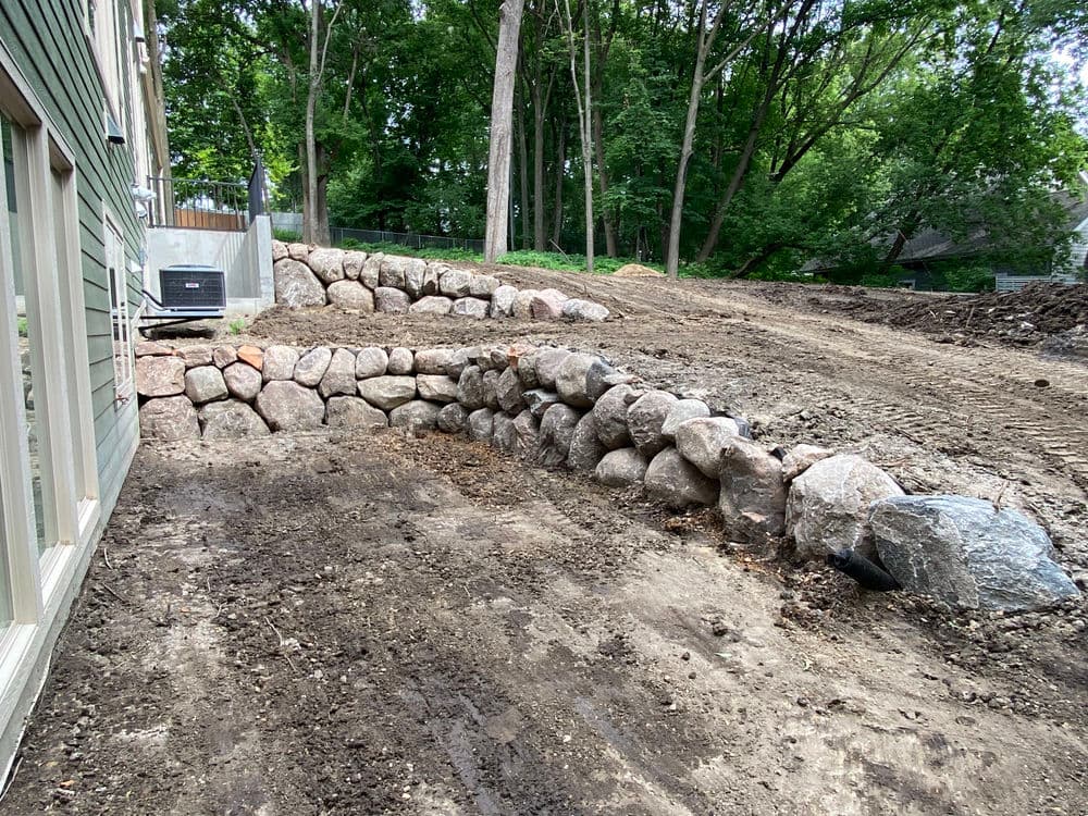Landscaped garden with stone retaining wall and cleared area ready for planting.